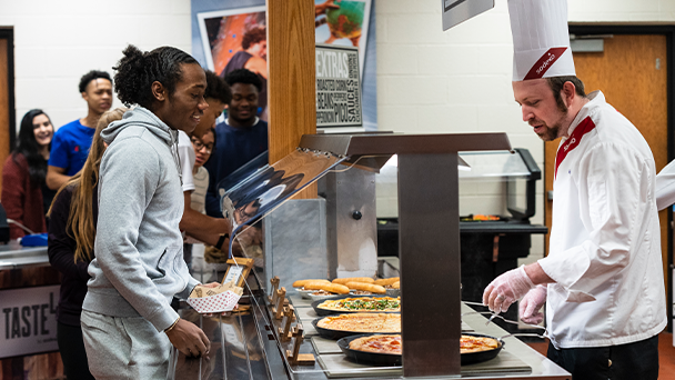 Chef serving delicious food to a group students