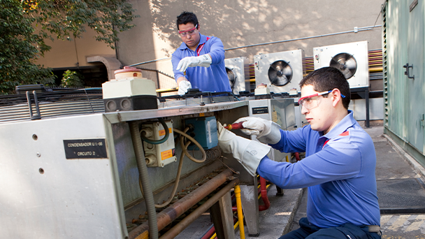 Two men repairing a large air conditioning unit in a professional setting