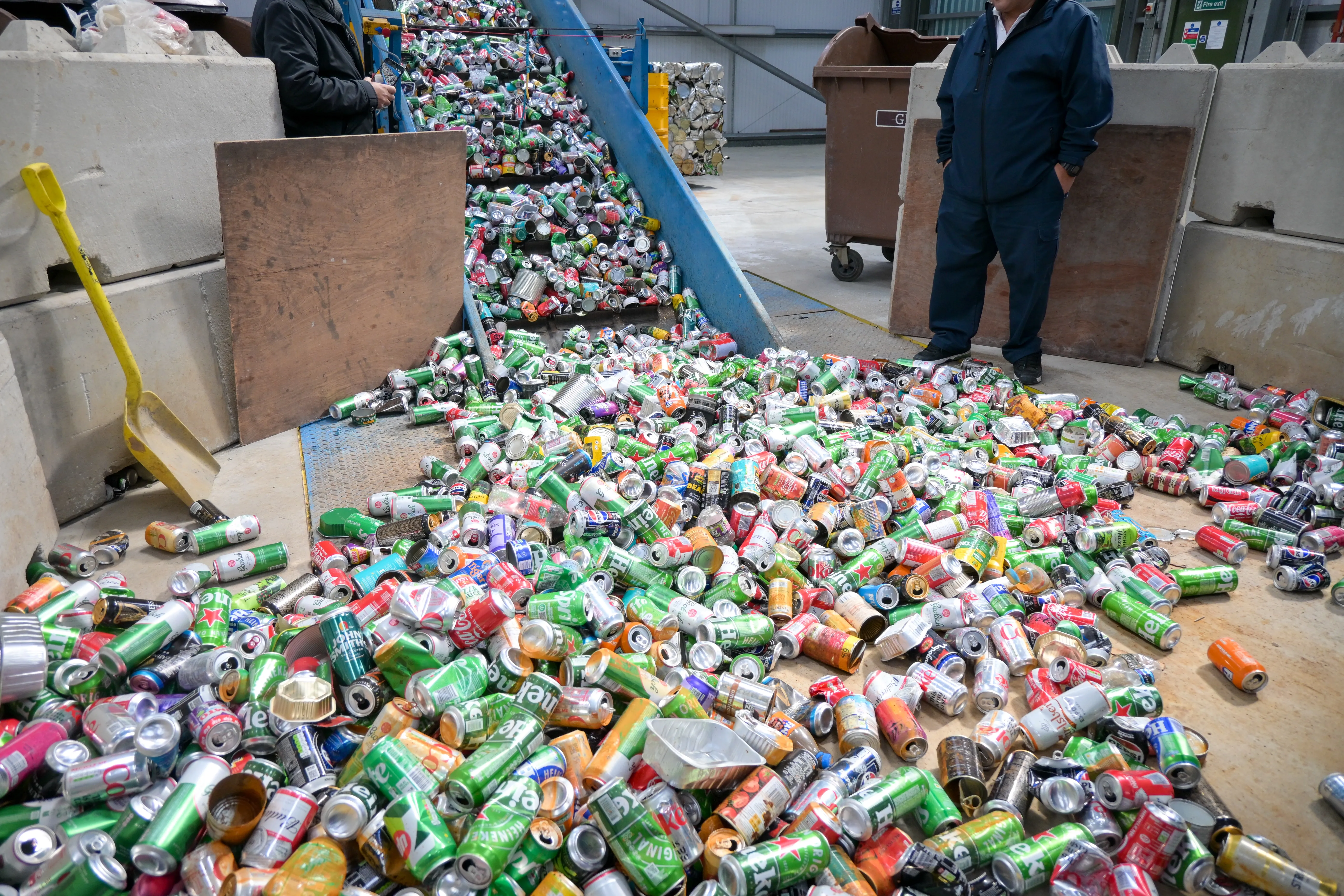 Aluminium drinks cans being processed on a conveyor and sorting area inside a recycling facility.