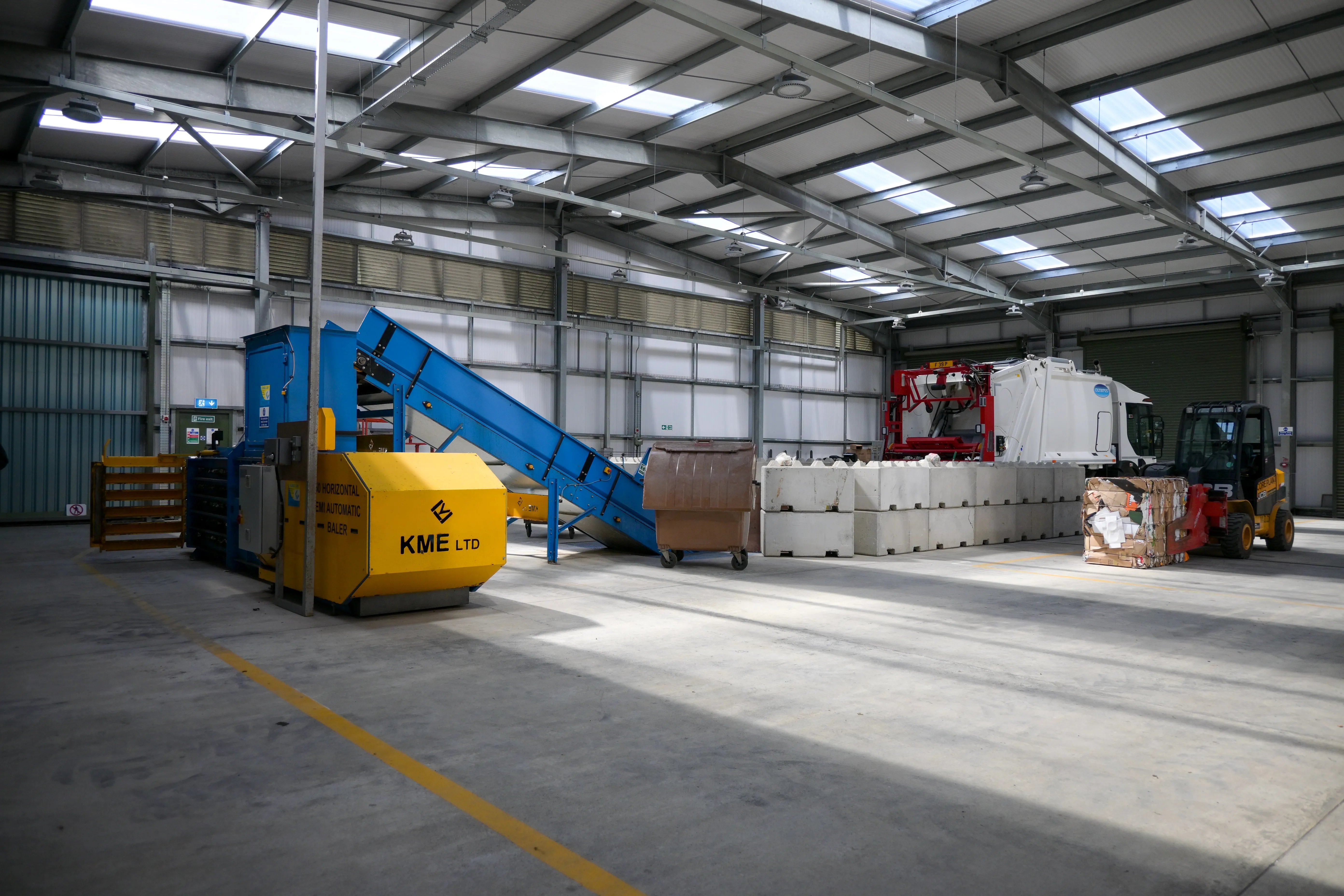 Recycling facility featuring an automated baling machine, storage containers and material handling equipment.
