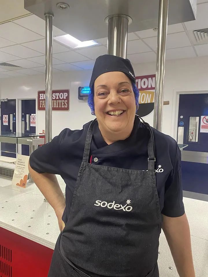 Person in catering uniform working in a food preparation area.