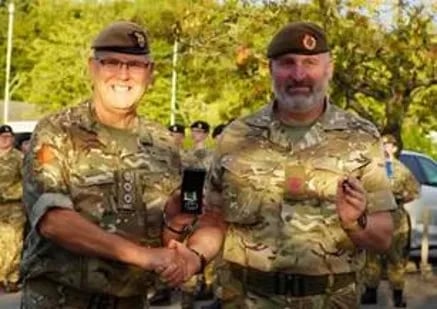 Two uniformed Army Cadet Force instructors posing together at an outdoor event, holding a medal or award.