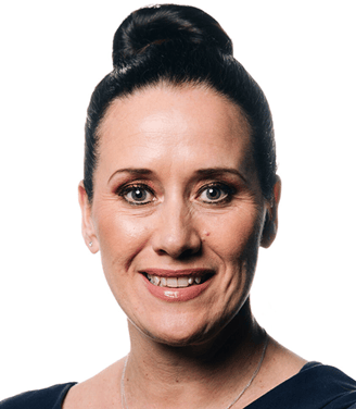 Professional head-and-shoulders portrait of a person with dark hair styled in a bun, wearing a black top against a light grey background. The image is evenly lit and cropped closely around the face and shoulders.