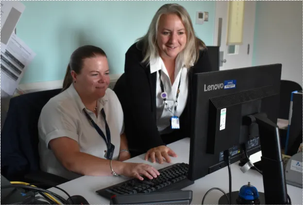 Two Sodexo colleagues working together at a desk while reviewing information on a computer screen.