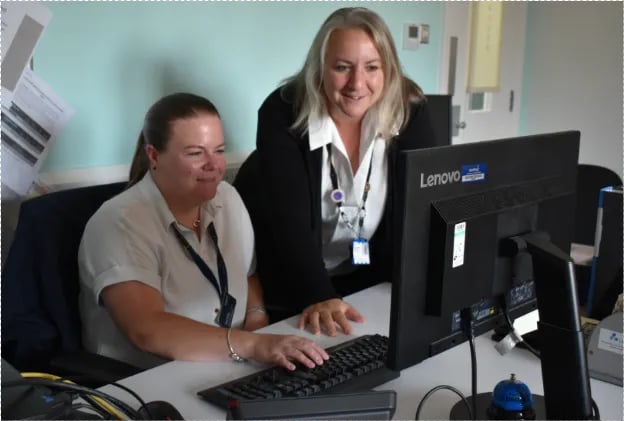 Two Sodexo colleagues working together at a desk while reviewing information on a computer screen.