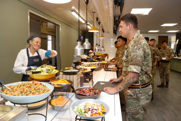 Soldiers waiting in line being served food.