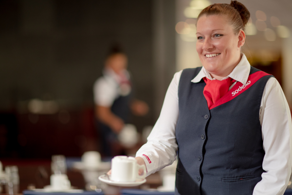 A woman in a uniform holding a coffee cup.