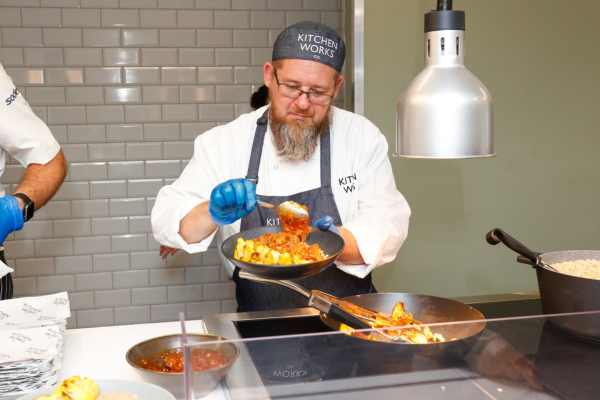 A chef serving food onto a plate.
