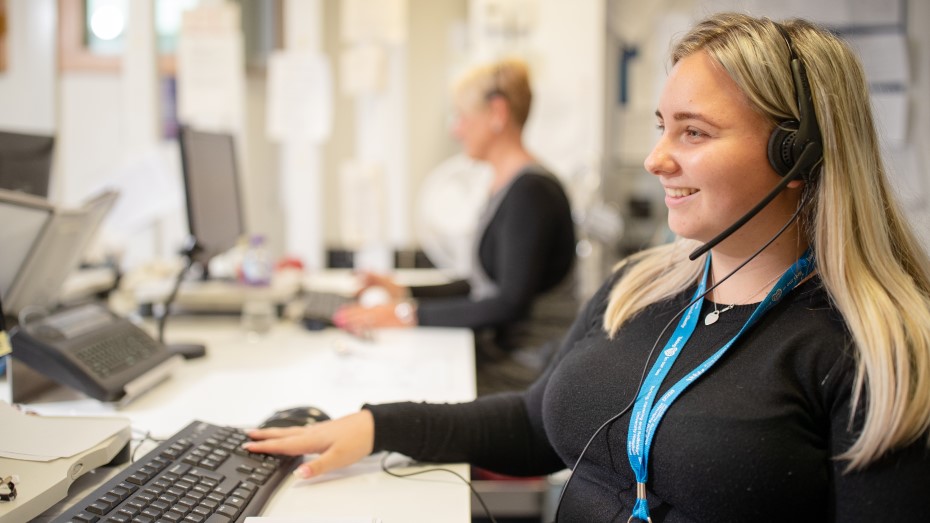 A woman with headphones on is working on a computer. 