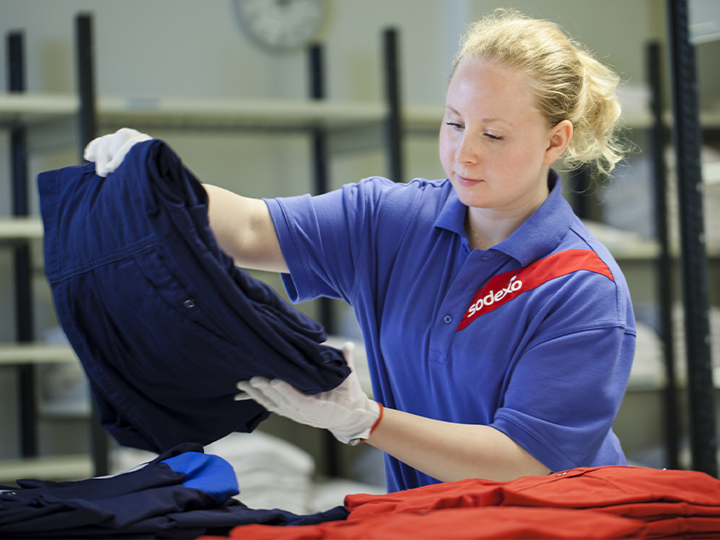 A Sodexo blond female worker holding a stack of clothes