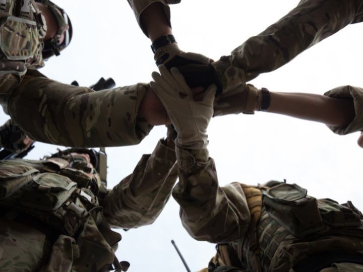 Soldiers in uniform forming a united front, holding hands together