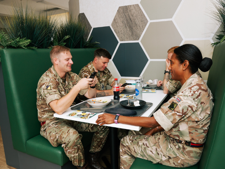 A diverse group military sitting around a wooden table, engaged in conversation and collaboration