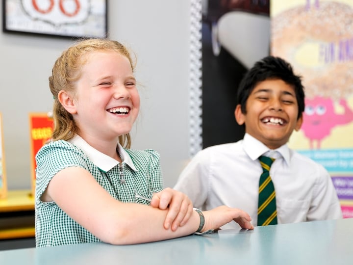 Two happy children sitting at a table, smiling