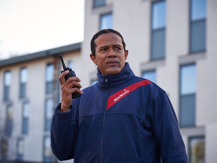 A man in a blue jacket holding a walkie talkie