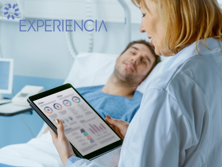Female doctor is using a tablet by a patient lying in a hospital bed