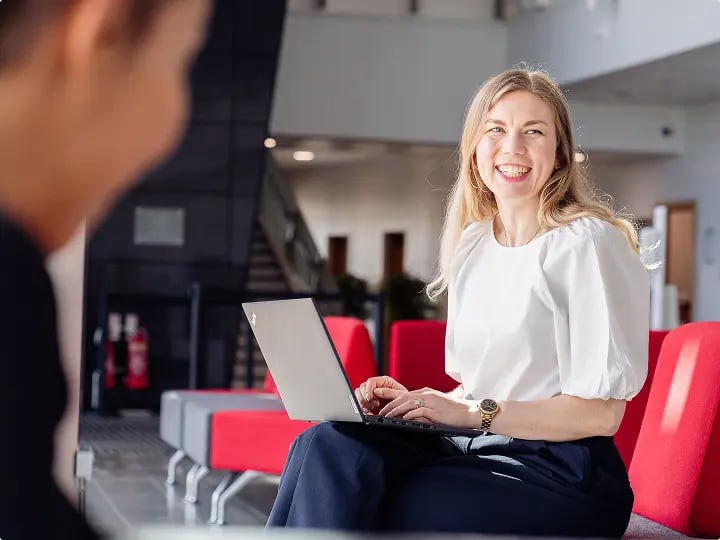 Person seated in a modern office lounge using a laptop, highlighting flexible working in a bright, contemporary public sector workspace.