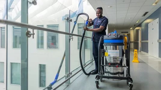 Healthcare cleaning operative using specialist equipment to clean and maintain a hospital corridor environment.