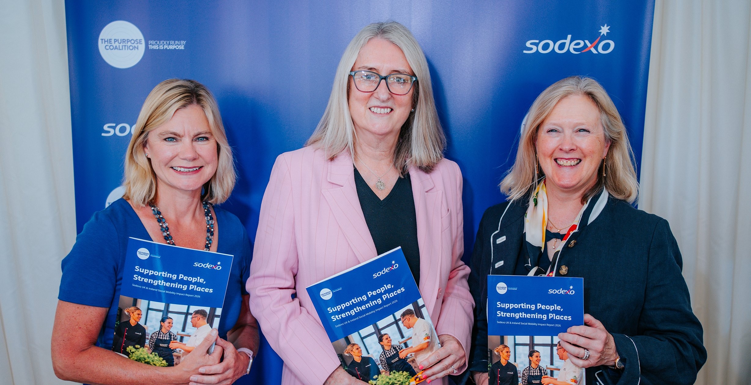 The Rt Hon Justine Greening, The Rt Hon Baroness Smith and Sodexo UK&I CEO Jean Renton stand in front of a blue Sodexo-branded backdrop, each holding a copy of the Purpose Coalition report. The report launch photograph features the three participants posing side by side with the publication prominently displayed.