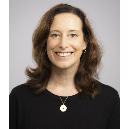 Professional headshot of a person with shoulder-length dark hair, wearing a black top and a pendant necklace, against a light grey background.