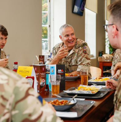 Group of soldiers smiling as they talk at a table with food trays