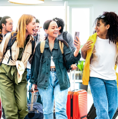 A group of young travelers walking and carrying backpacks and suitcases