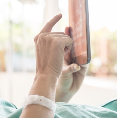 Hnads of a patient is interacting with a tablet