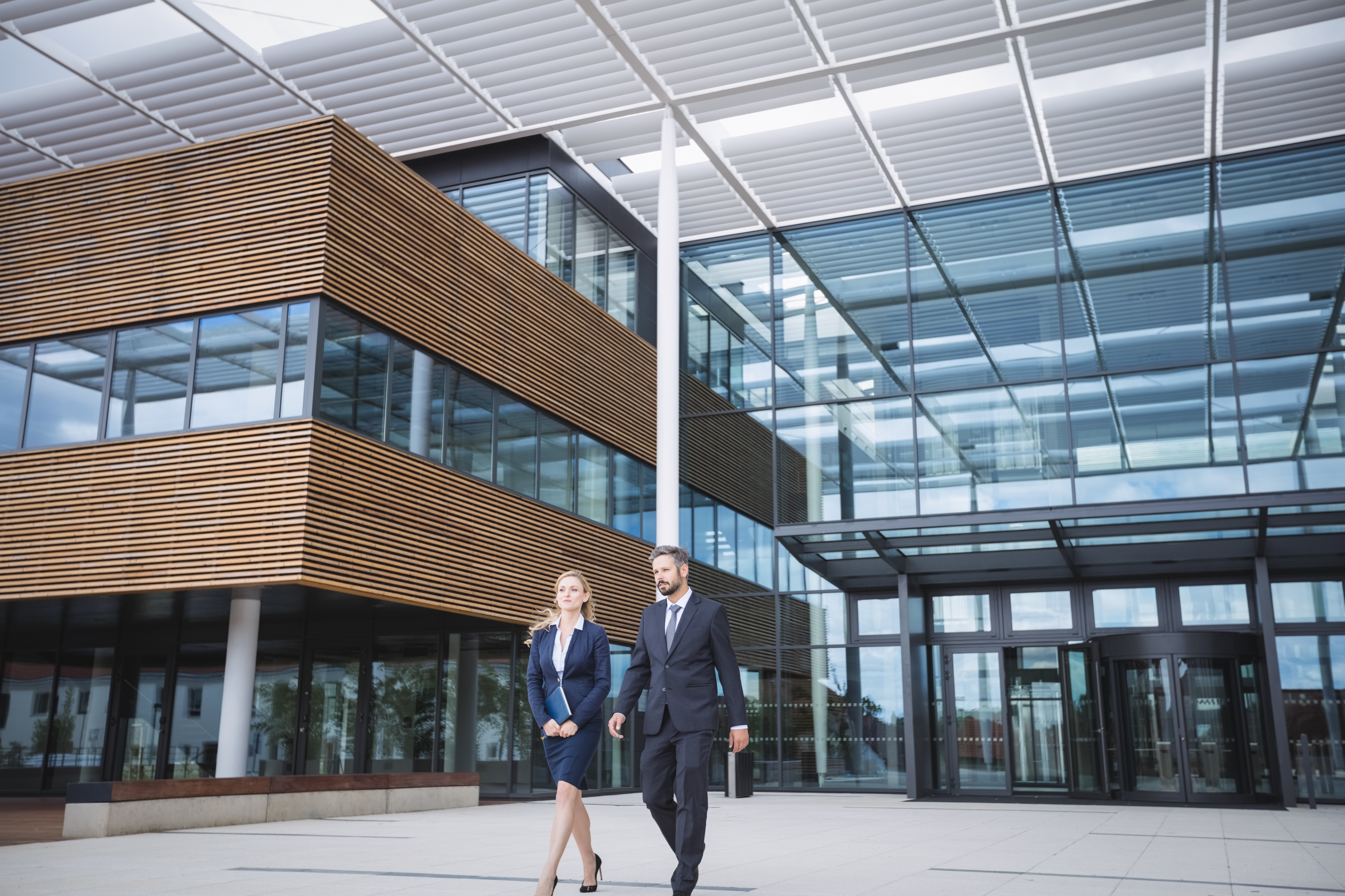 businessman-walking-with-colleague-outside-office-building