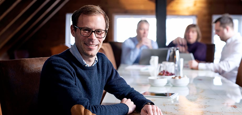 aksjeselskap med organisasjonsnummer. Møterom med mennesker rundt et langt bord.