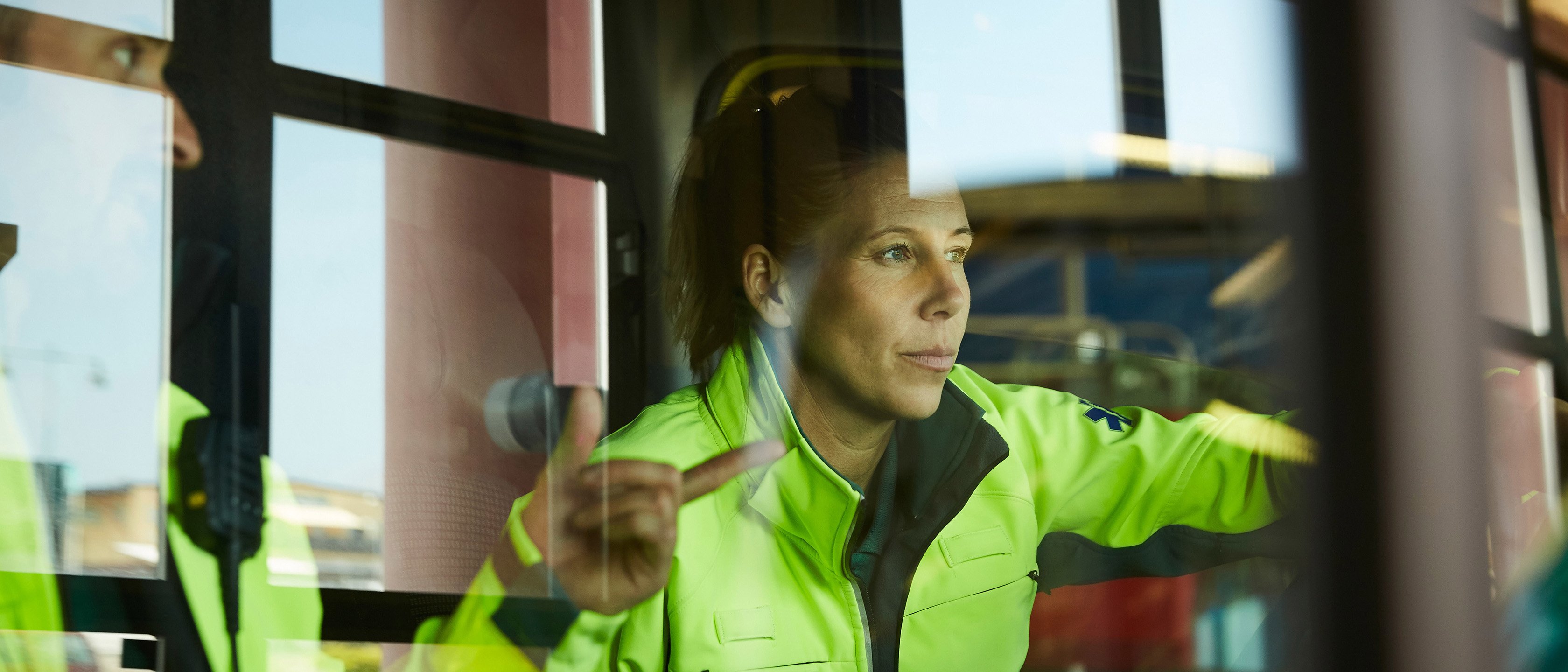 Lån og finansiering: Dame i arbeidsklær ser ut vinduet i industribygning.