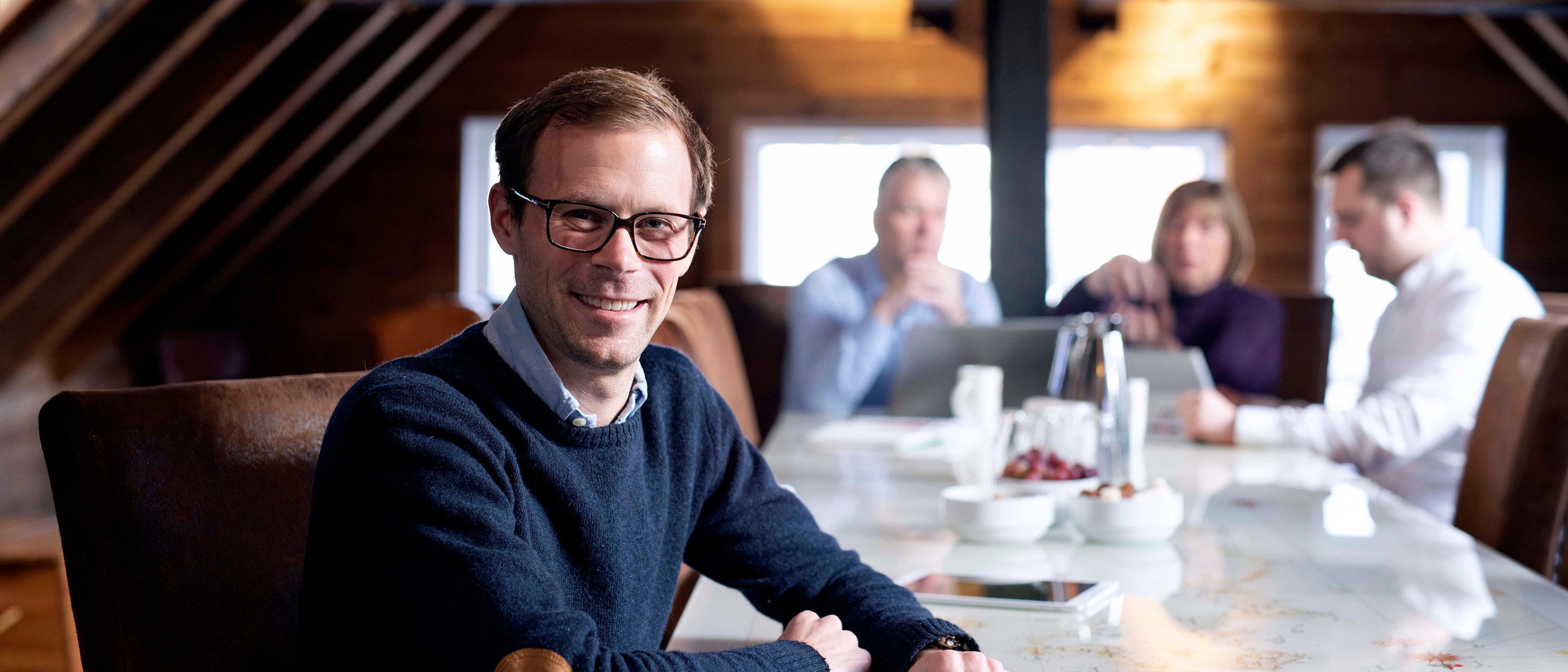 aksjeselskap med organisasjonsnummer. Møterom med mennesker rundt et langt bord.