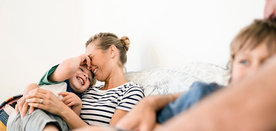 Smilende familie slapper av i sofa. Fornøyd med skadeoppgjøret til Frende.