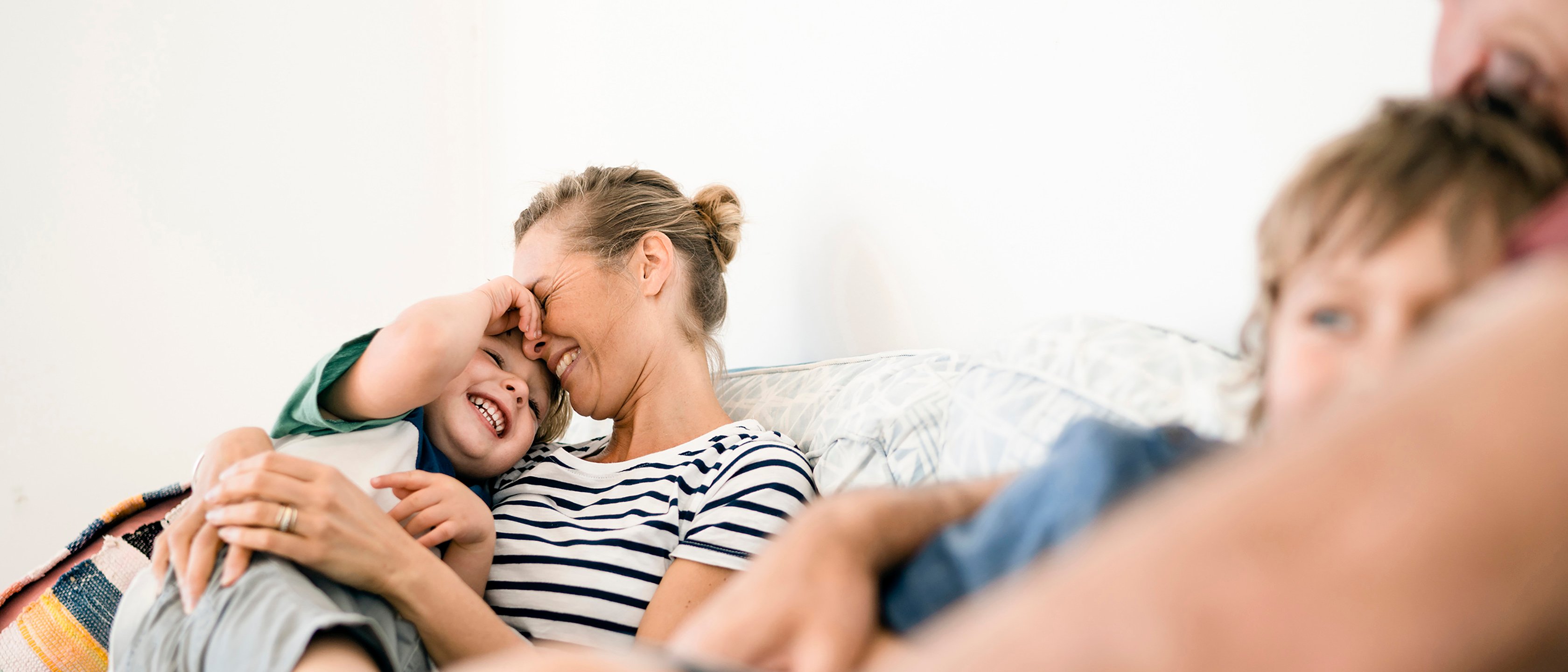 Smilende familie slapper av i sofa. Fornøyd med skadeoppgjøret til Frende.