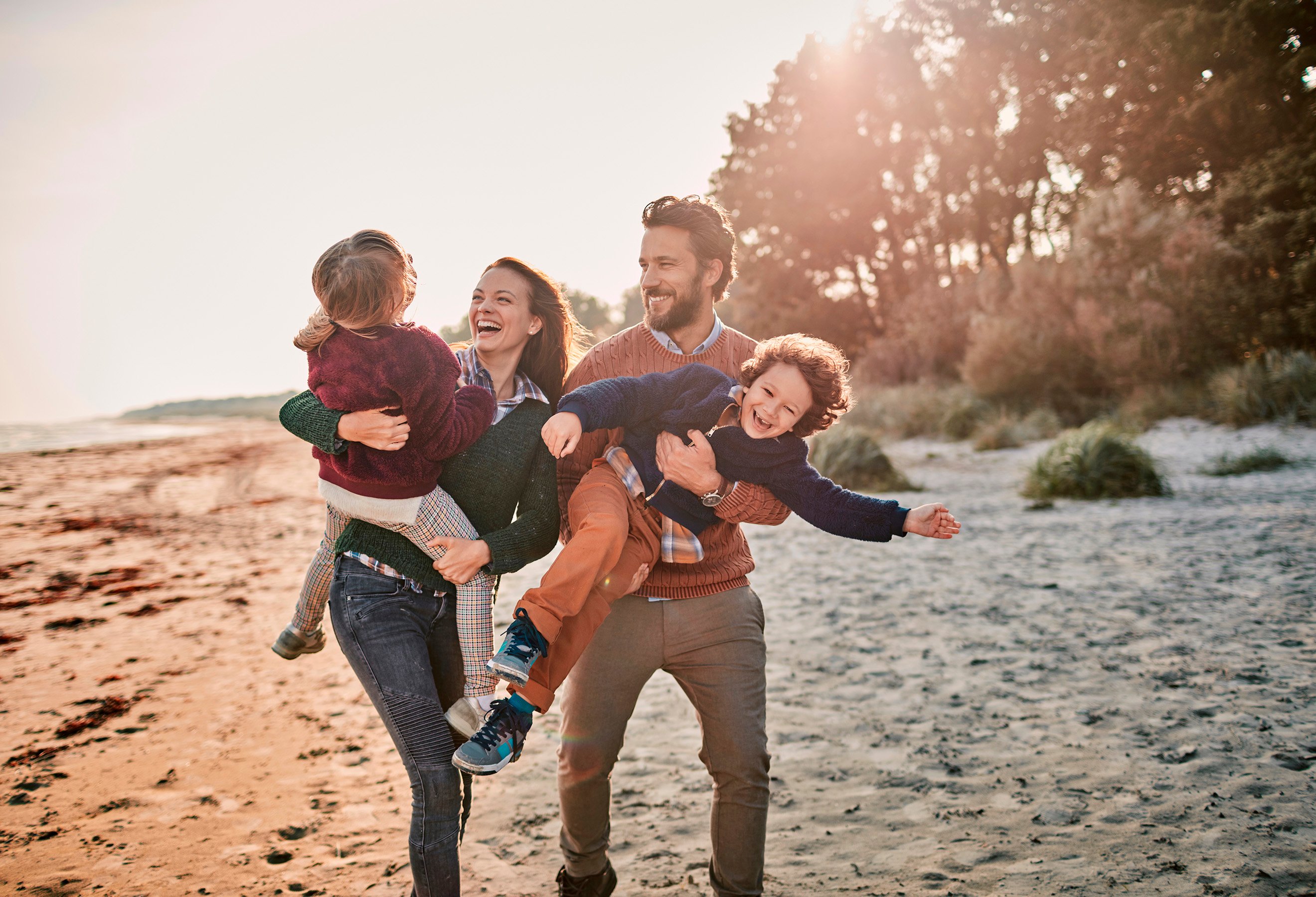 Familie på fire på strand i solnedgang