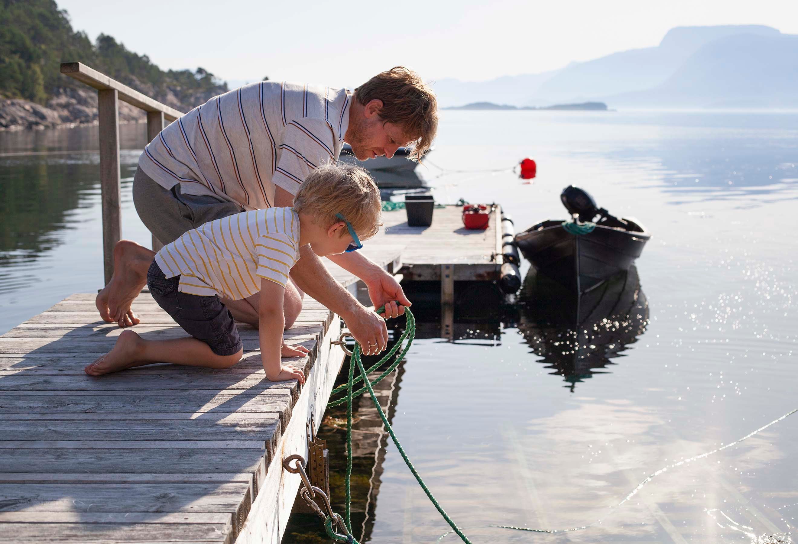 Båtforsikring: Far og sønn på brygga med båt i bakgrunnen