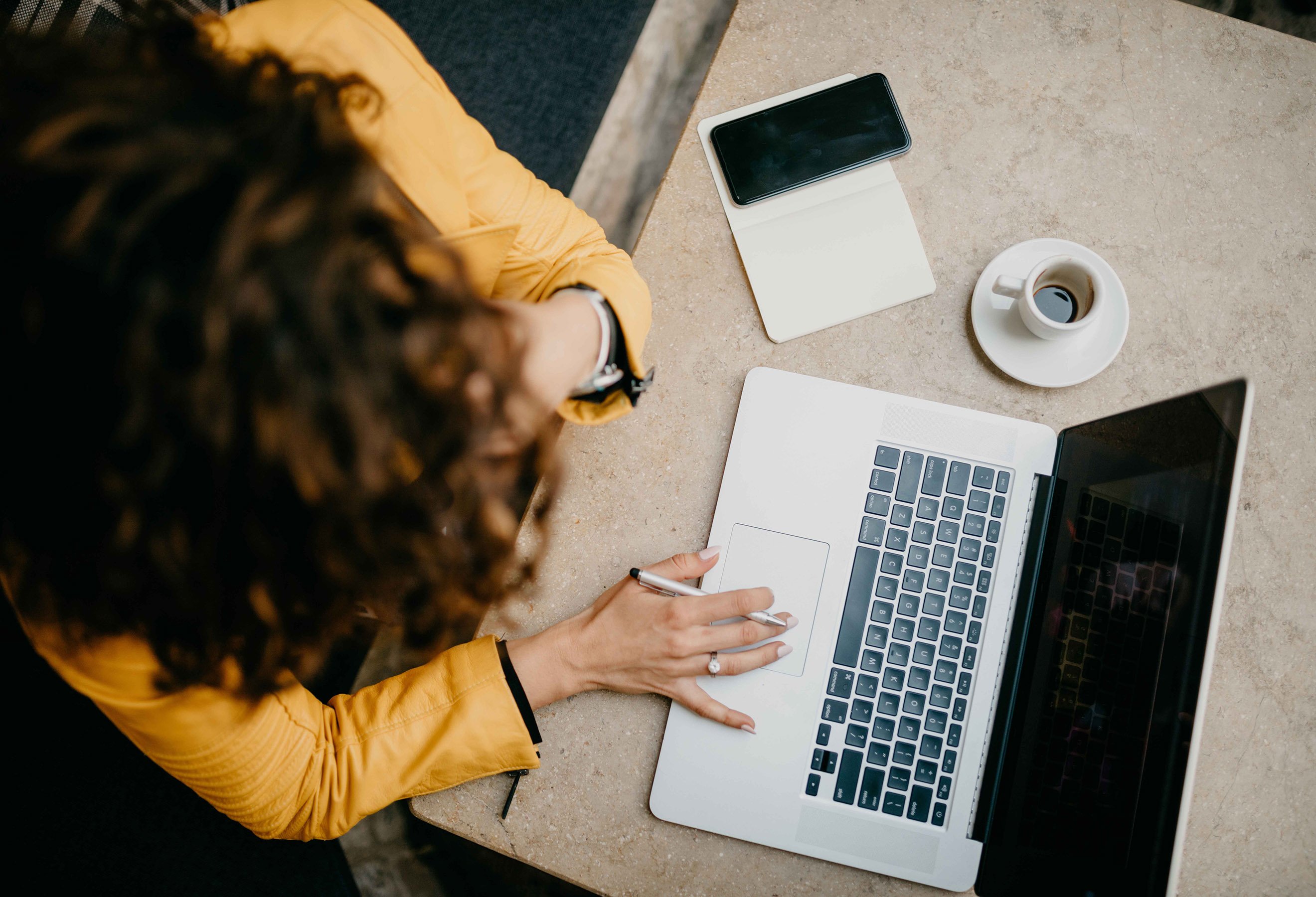 Avtalegiro: Bilde tatt ovendra av dame foran laptop, kaffekopp og mobil ved siden av seg. 