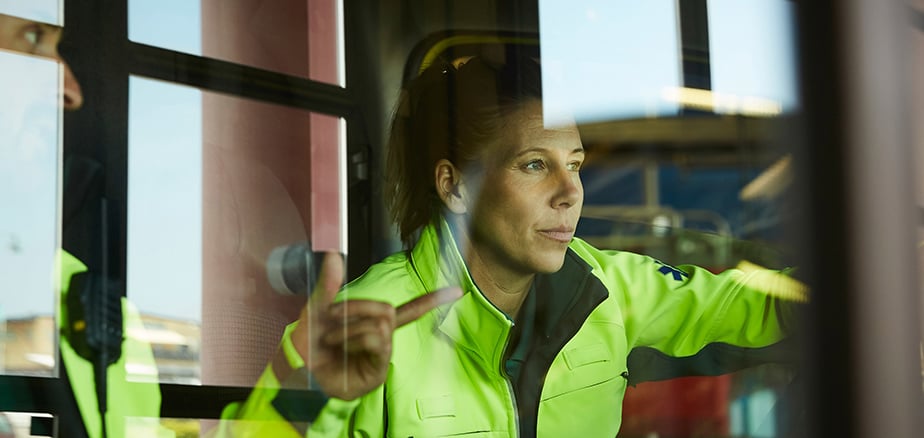 Lån og finansiering: Dame i arbeidsklær ser ut vinduet i industribygning.