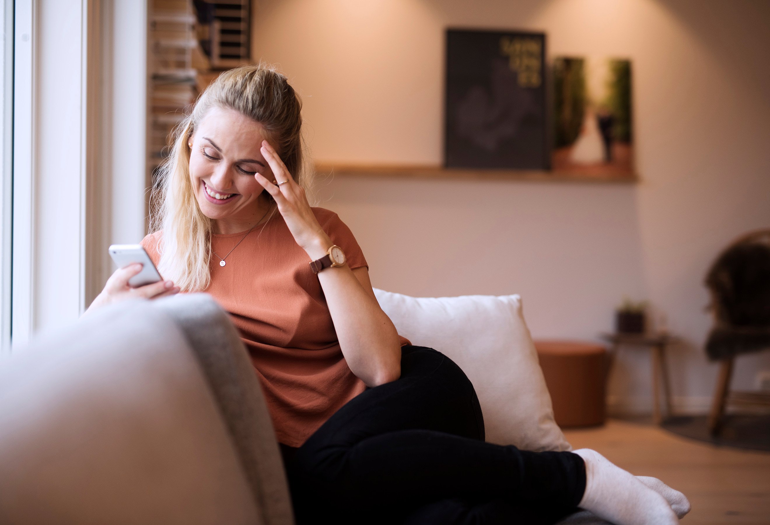 Dame sjekker appen på mobil i sofa