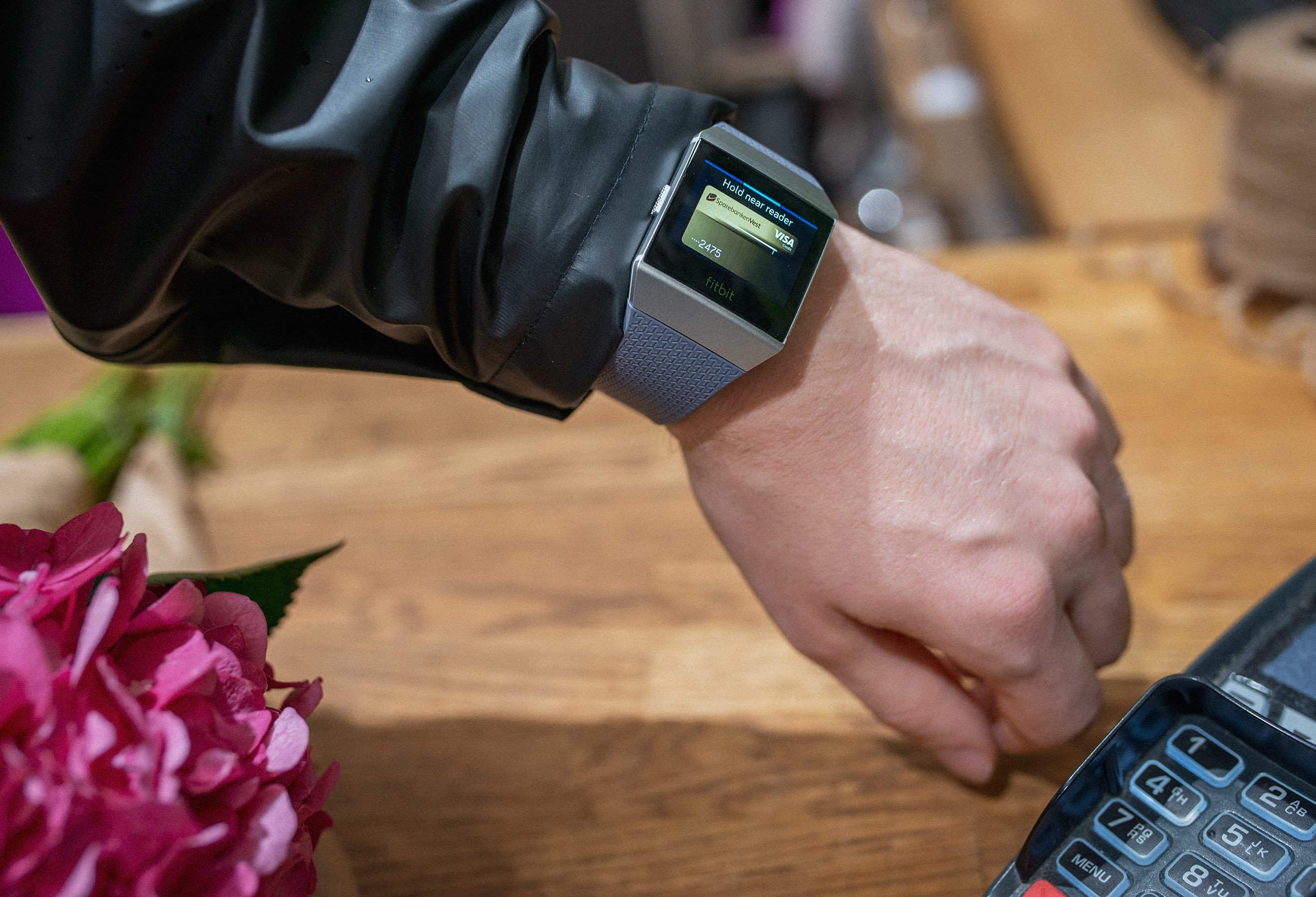 Betaling med Fitbit Pay - hånd med Fitbit og Visa Gull