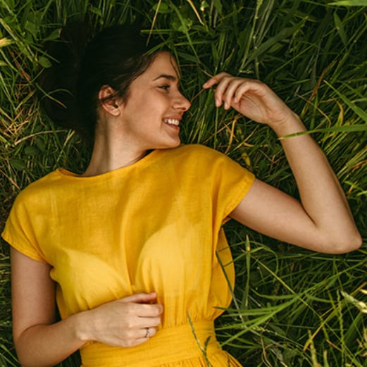 Jente med gul kjole drømmer i gresset
