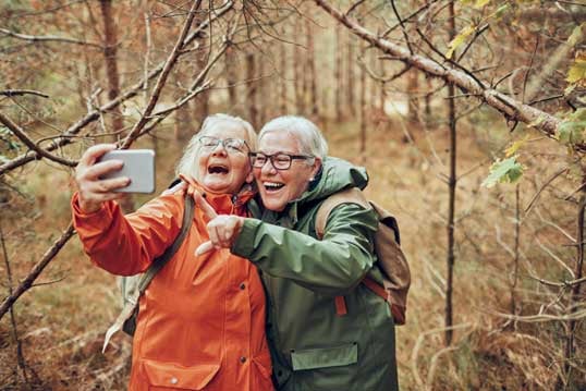 Seniorlan - to eldre damer tar selfie ute i naturen