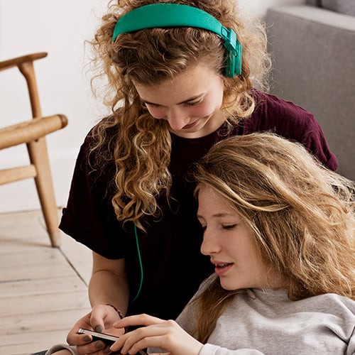 To unge jenter ser på mobil.