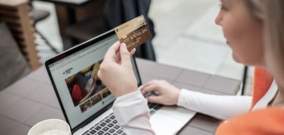 Jente foran PC holder Visa Gull kredittkort i hånden