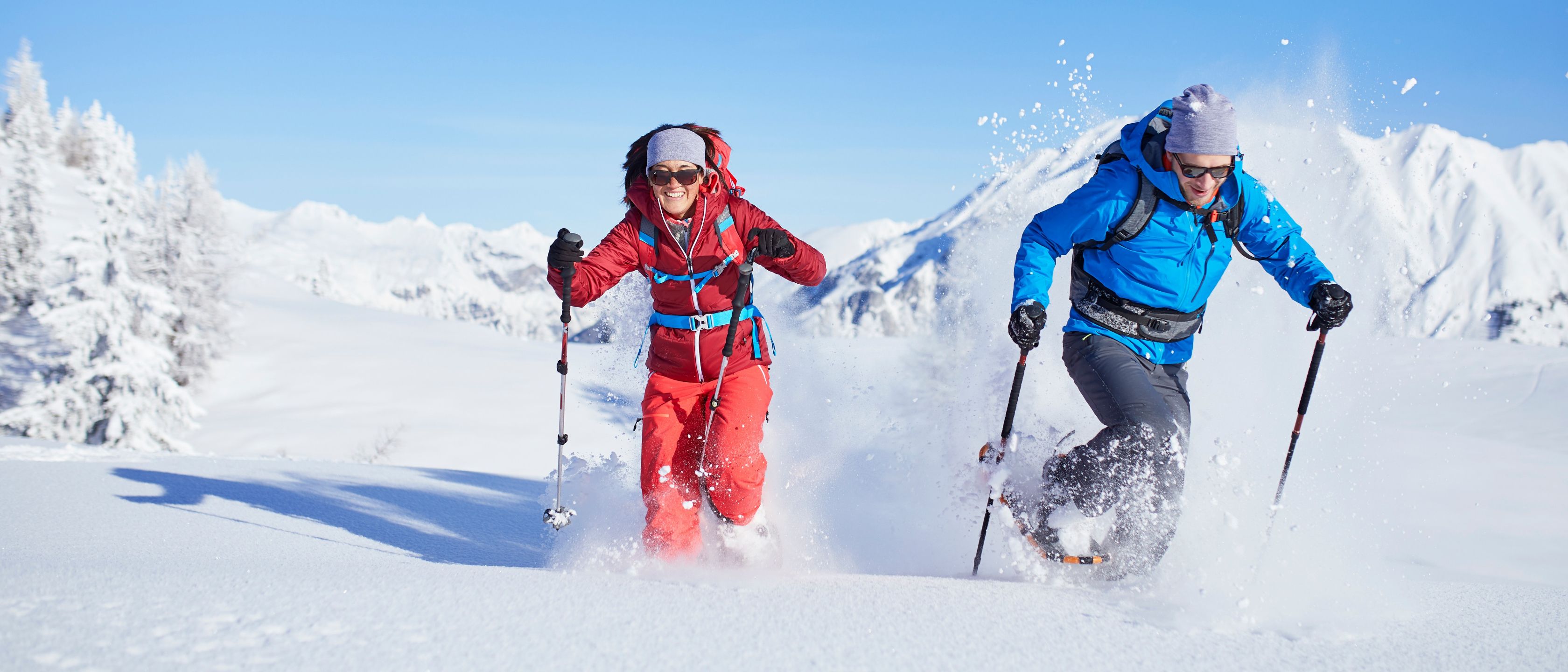 Dame og mann som går i snø med truger og staver