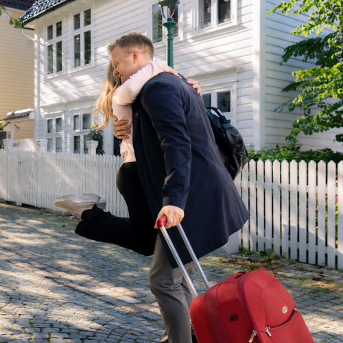 Far med reisekoffert som klemmer datter