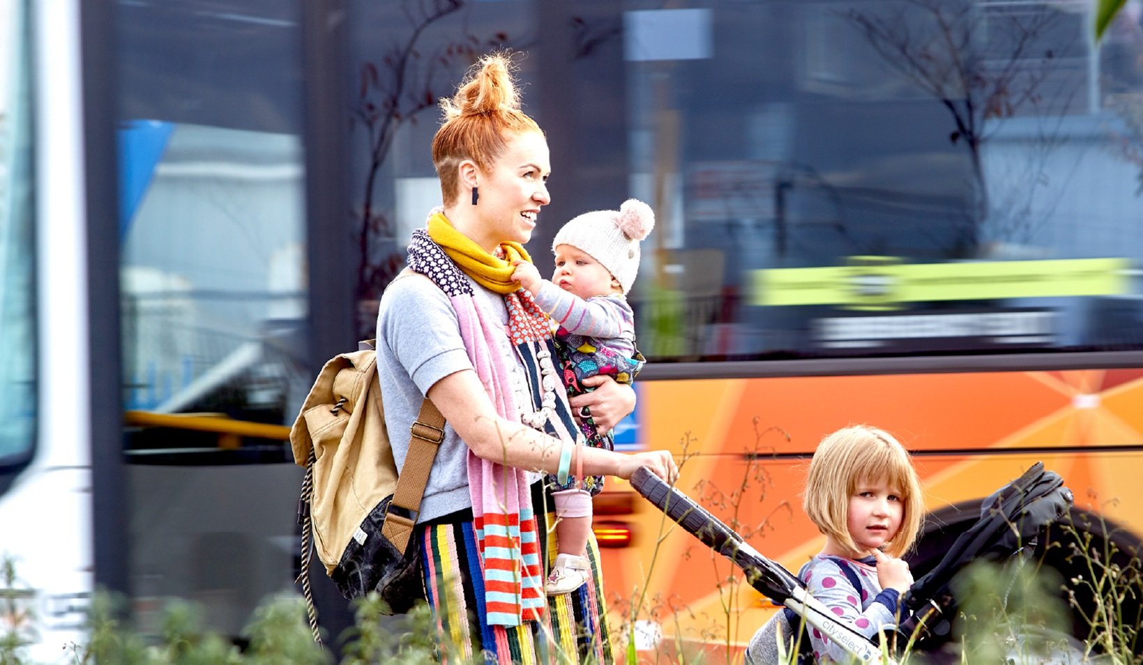 Image of a women and two children in front of a bus