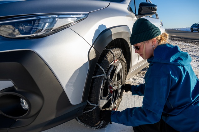 Image of a person installing chains on the car wheel
