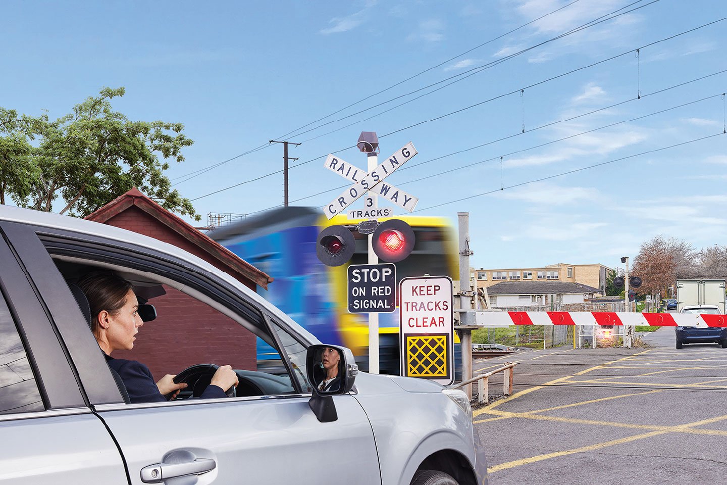 Image of a car stopped at a level crossing with lights flashing and train passing