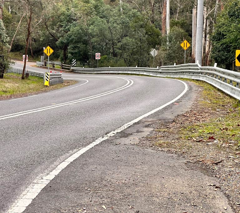 Image of a bend in a country road with barriers along one side
