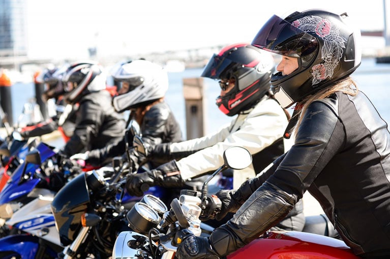 Image of motorcyclists wearing helmets and safety gear lined up side by side