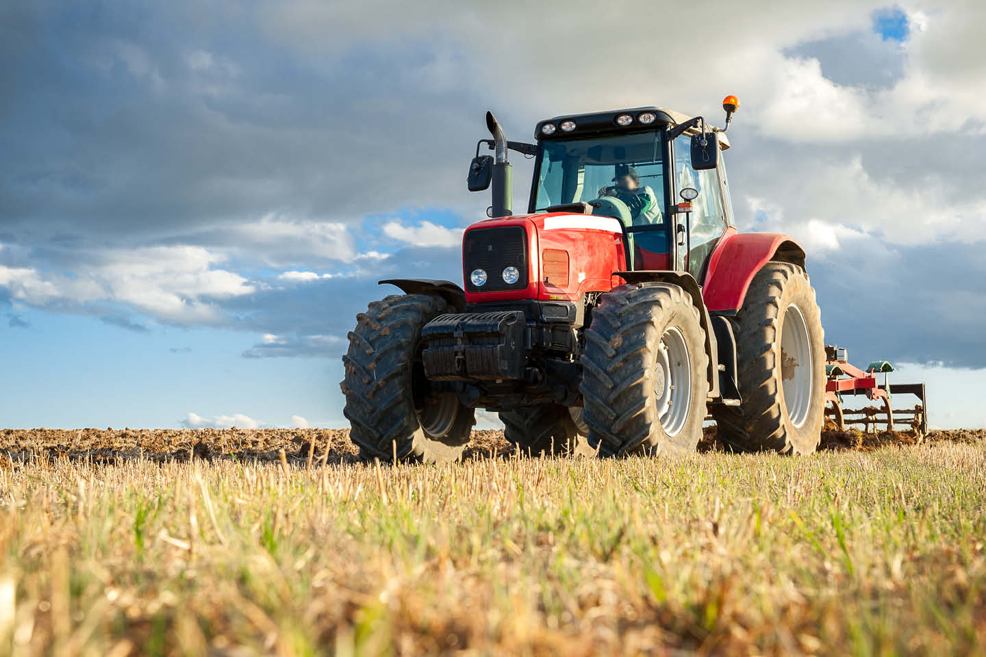 Photograph of a red tractor, plouging a field
